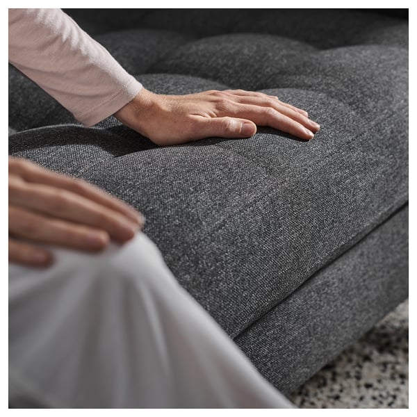 Person adjusting cushions on a dark grey MORABO sofa, which is sleek and modern with a fabric cover.