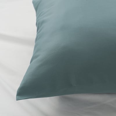 A smooth, teal pillowcase with subtle, textured wave patterns. Shows high-quality fabric and craftsmanship.