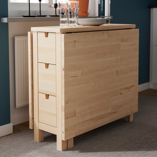 Light wood dining table with drawers, featuring a drop-leaf design for space efficiency, supporting up to four chairs.