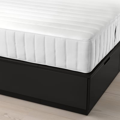Bed with white mattress on black under-bed storage.