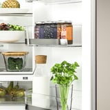 Fridge with clear glass storage, showing fresh veggies, fruits, and containers.