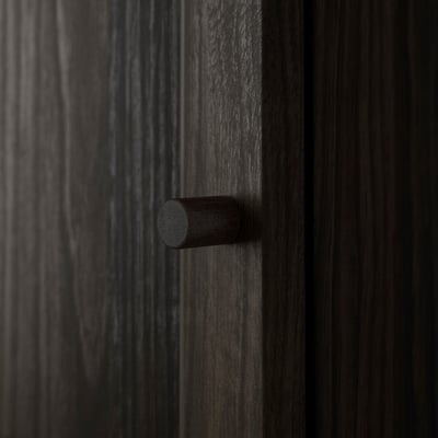 Black wooden panel with cylindrical handle, smooth finish and sleek design, part of furniture set.