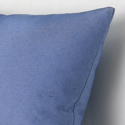Blue pillow with recycled materials, visible stitching, laid on textured background. Quality craftsmanship shown.