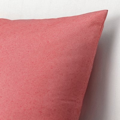 A close-up of a red cushion cover. The texture shows recycled cotton fibres, appearing slightly varied in colour, giving it a unique look.