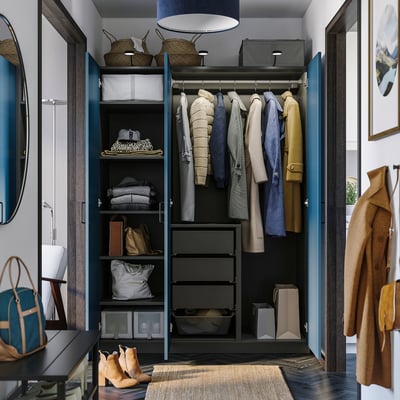 Open wardrobe displaying coats, folded clothes, and organisers. Floor-length mirror is placed beside the wardrobe.