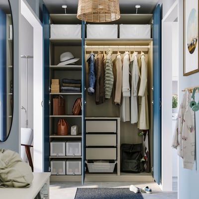 Well-organized closet with coats, bags, and shelves; hanging storage, drawers, and a light fixture.