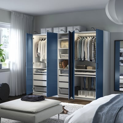 Modern bedroom with blue wardrobe, organised clothes, white bench, and grey bed.