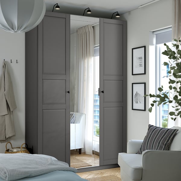 Modern bedroom with grey PAX wardrobe, mirrored doors, lights, and plants.