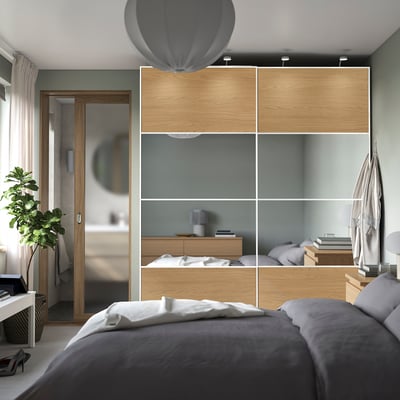 Modern bedroom with PAX wardrobe & grey bedding, bathroom entrance.