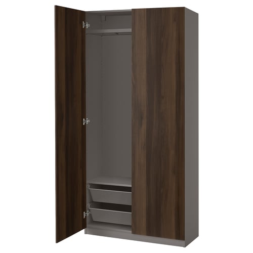 A tall, dark brown PAX wardrobe with grey interiors and mesh shelves, featuring soft-close doors.