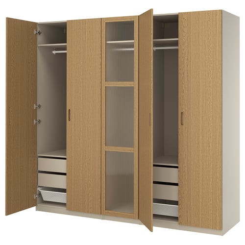 A light brown wooden PAX wardrobe with open doors, showcasing an adjustable interior with hanging rods, drawers, and a mesh basket.