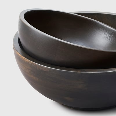 Set of wooden bowls, dark finish, stacked neatly, smooth texture, natural grain visible.