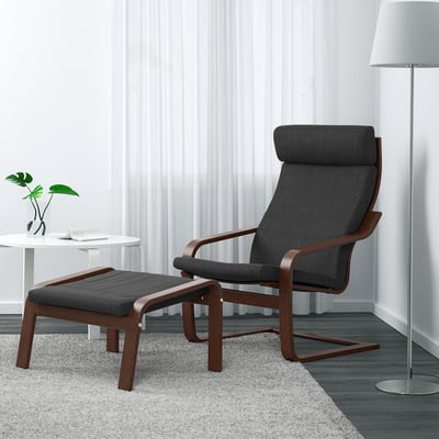 Dark grey POÄNG armchair & stool, wood frame, reclining, in modern room with lamp & plant. Armchair is large, matches white curtain height.