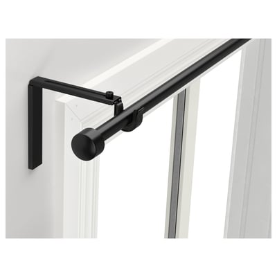 Black RÄCKA curtain rod, adjustable, modern design, mounted on white wall near window.