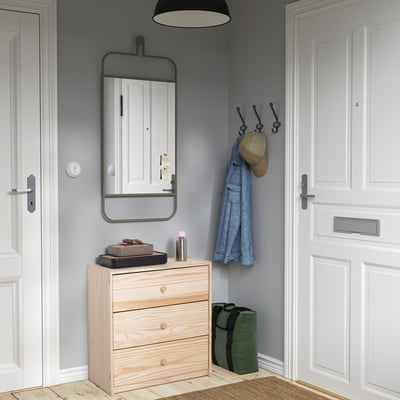 Small wooden RAST chest fits neatly between doors. Light wood, three drawers, modern design.