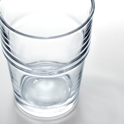 Clear glass cup, small amount water, thick base, stacked neatly.