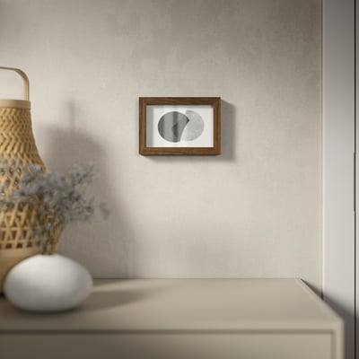 Minimalist photo frame with plastic front, hangs on textured wall, holds photos close or deep.