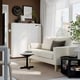 Modern living room with SALTSJÖBADEN sofa, minimalist design, by large window, tall cabinet with decor.