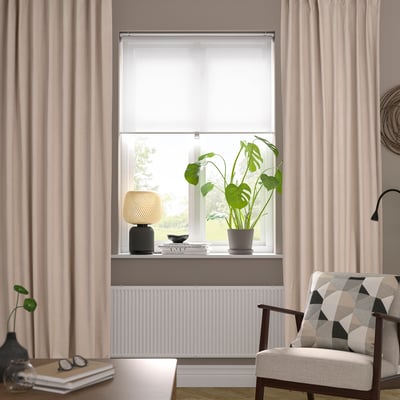 Modern living room with beige SANELA curtains, geometric throw on cosy chair.