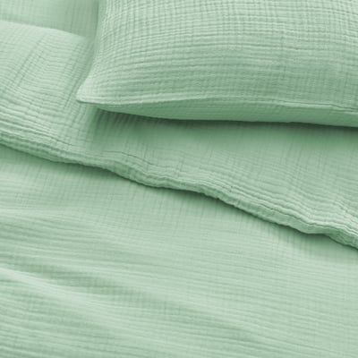 Light green bedding set, neatly arranged. Soft, organic cotton with visible stitching, showcasing quality and craftsmanship.