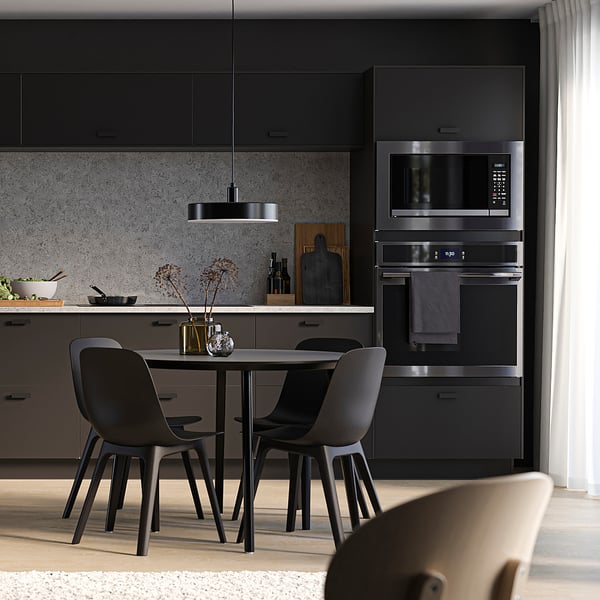 Modern kitchen with black SEKTION cabinets, grey countertop, built-in oven, microwave, and black dining set.