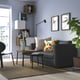 Stylish living room with grey skonaback sofa, colourful pillows, coffee table, plant, bookshelf, and wall frames.