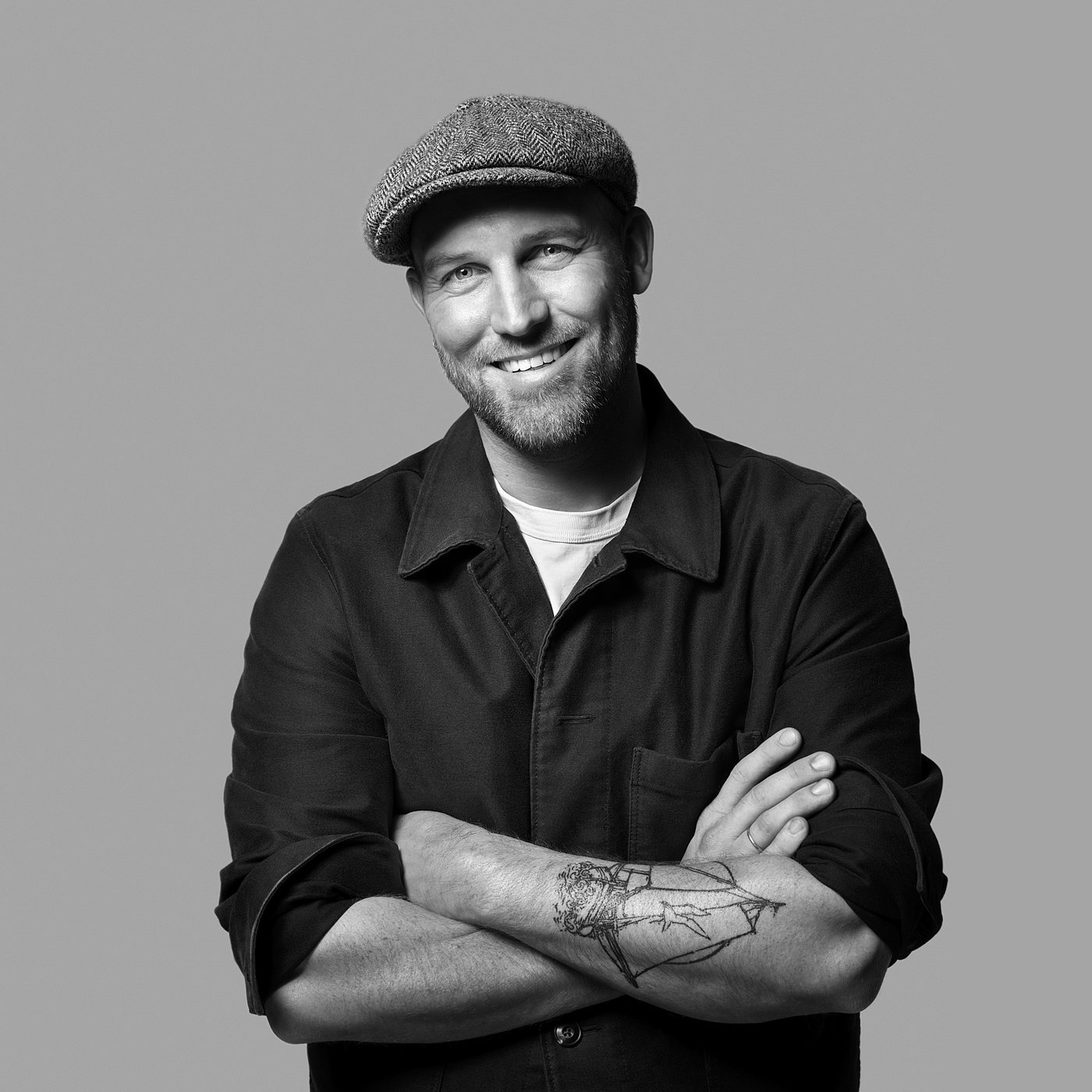 Black and white portrait of Friso Wiersma wearing a cap and jacket, with a visible tattoo on the forearm.