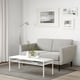 Minimalist living room with retro grey sofa, coffee table with flowers, and striped rug.