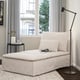 Modern minimalist white chaise lounge under black floor lamp; beside small black table with flowers and books.