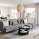 Modern living room with grey sofa, black coffee table, pendant light, rug, and plants.