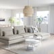 Modern living room with grey SÖDERHAMN sofa, coffee tables, blue rug, and large window.
