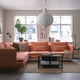 Modern living room with peach SÖDERHAMN sofa, large windows, pendant lamp, rug, plant, and coffee table. Bright and inviting.