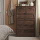 Brown SONGESAND chest, 6 drawers, classic design for beside bed. Space-efficient with lamp and vase decor.