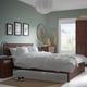 Serene bedroom with SONGESAND dark brown wooden bed, nightstands, dresser, and wardrobe. White bedding, green walls, and natural light from a window.