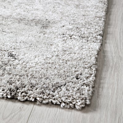 Soft, plush grey rug on wooden floor, showing dense texture and comfort.