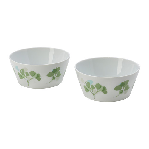 Two white bowls with green leaf designs, made of porcelain. One is wider, the other deeper, both with a smooth finish.