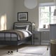 Modern bedroom with STJÄRNÖ bed, high headboard, wooden bedside table, lamp, radiator, and cosy light from window.