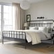 Black STJÄRNÖ bed, curved headboard, white linens, large window
