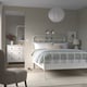 Modern bedroom: STJÄRNÖ bed w/ headboard & lyngör base. White bed against grey walls, chair on rug, dresser & mirror.