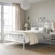 White STJÄRNÖ bed with large headboard in minimalist room, beside a window with sheer curtains.