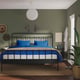 Cosy bedroom: black metal STJÄRNÖ bed with blue linens, green walls, and hanging lamps. Beside table and plants nearby.