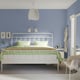 Modern blue bedroom with white STJÄRNÖ bed, green linens, hanging light, bedside table, and a small chair nearby.