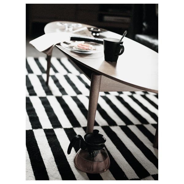 Black and white striped rug under a wooden table with plates and a mug on top.