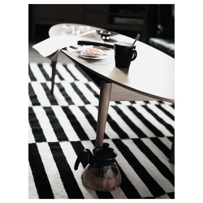 Black and white striped rug under a wooden table with plates and a mug on top.