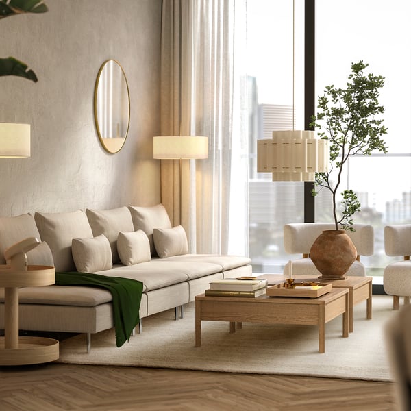 Modern living room with white rug, beige sofa, coffee table, and city view window.