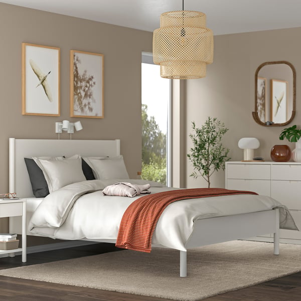 Modern bedroom with white STOENSE rug, comfy bed, beige walls, plants, & pendant light.