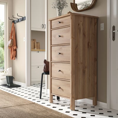 Light wood STOREMOLLA chest with six drawers, vase, hooks, and tiled floor.