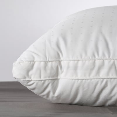 Close-up of a white, luxurious pillow with intricate piping detail and soft fabric, showcasing high-quality comfort and craftsmanship.