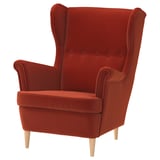 A red, velvety STRANDMON wingback armchair with wooden legs, featuring a high back and cushioned seat for comfort.