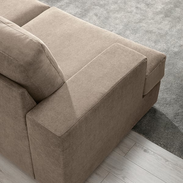 Tan sofa with cushions on a rug and wooden floor.